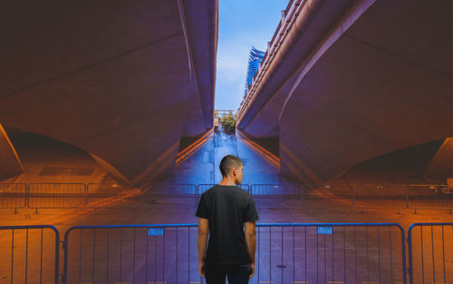 Rear view of man standing by railing in city