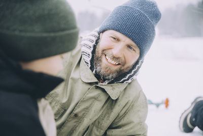 Happy mature man wearing knit hat talking with boy