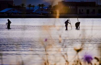 Silhouette people on water against sky