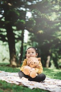 Portrait of cute boy sitting on toy against trees