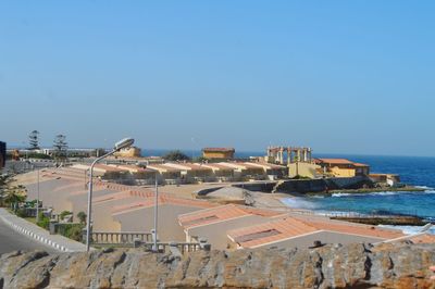 Aerial view of city by sea against clear blue sky