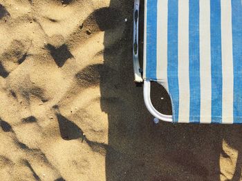 Cropped image of deck chair on sand at beach