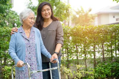 Smiling mother and daughter looking away while standing outdoors