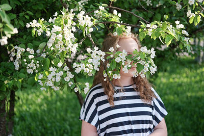 Portrait of woman standing by flowering plants