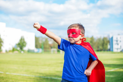 Boy in superman costume standing on road against sky