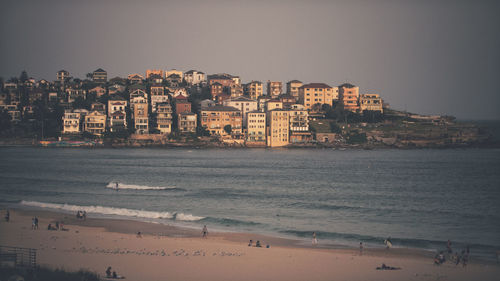 Buildings by sea against sky at dusk