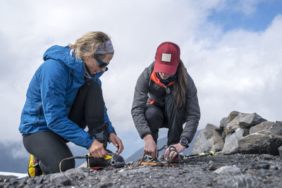 A female mountaineer explains how to put on cramp ons at base camp, mt. baker