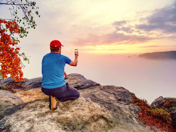Male traveler using mobile cell phone sharing fall mountains view for friend through social network