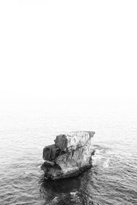 High angle view of rock structure in sea against clear sky