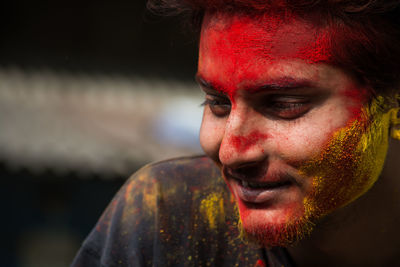 Close-up of smiling young man with powder paint on face during holi