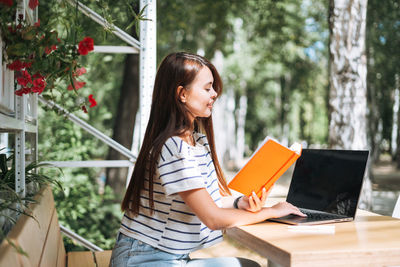 Young woman using laptop while sitting at park