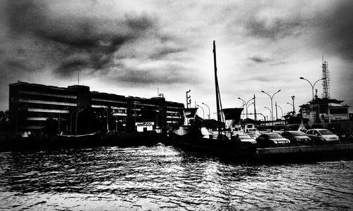 Boats in harbor against cloudy sky