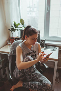 High angle view of woman using smart phone while sitting at home