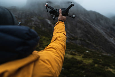 Rear view of person holding drone on mountain