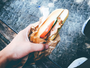 Cropped image of hand holding hot dog on street