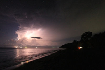 Firework display over sea against sky at night