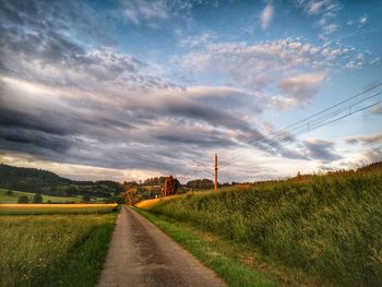 Road amidst field against sky