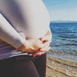 Close-up midsection of pregnant woman at beach