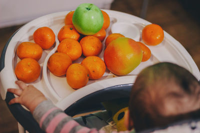 Cute baby sitting by fruits