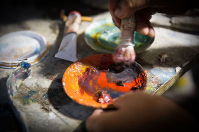 Cropped hands of artist mixing paint in plate