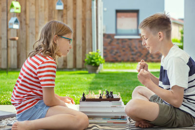 Rear view of siblings sitting outdoors