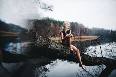 Woman with arms raised against trees against sky