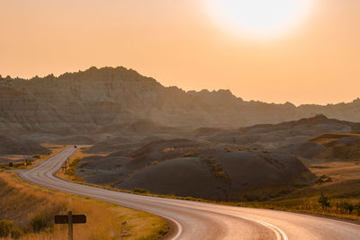 Scenic view of road by mountains against clear sky