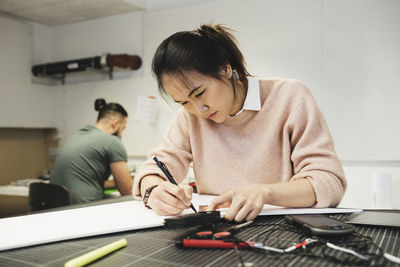 Female engineer working on paper at table in workshop