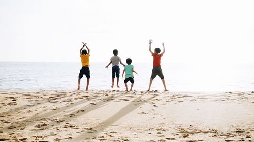 Rear view of people on beach against clear sky