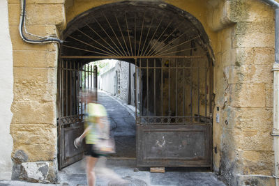Blurred motion of woman walking by building