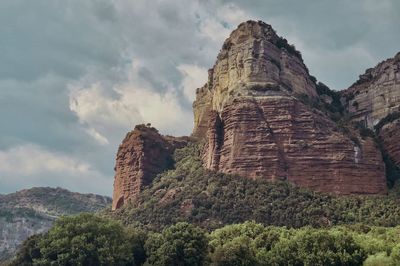 Rock formations on mountain against cloudy sky