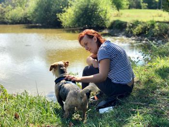 Woman with dog by lake on field