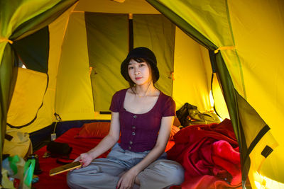 Portrait of young woman sitting in tent