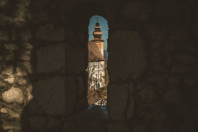 Church seen through window on stone wall