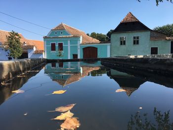 Reflection of building in lake against clear blue sky