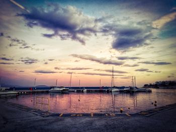 Sailboats moored at harbor against sky during sunset