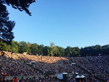 Crowd at music concert against clear blue sky