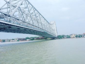 Bridge over river against sky in city