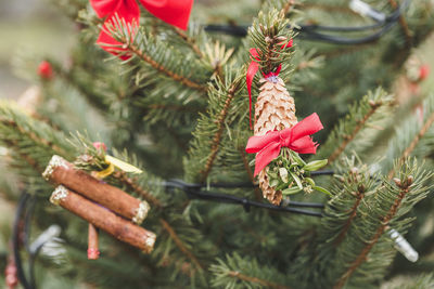 Diy handmade pine cone and ribbon bow decoration on christmas tree