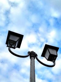 Low angle view of lamps against cloudy sky