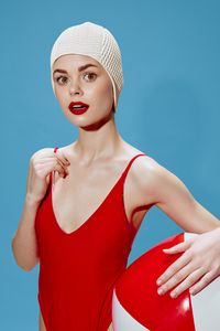 Portrait of smiling young woman standing against blue background