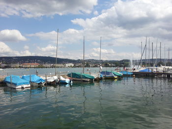 Boats moored at harbor against sky