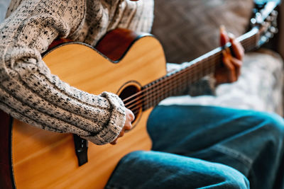 Midsection of woman playing guitar