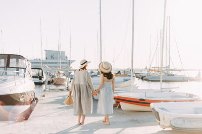 Rear view of women at harbor against clear sky