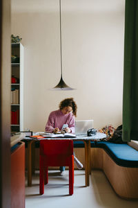 Full length view of young woman doing homework at table