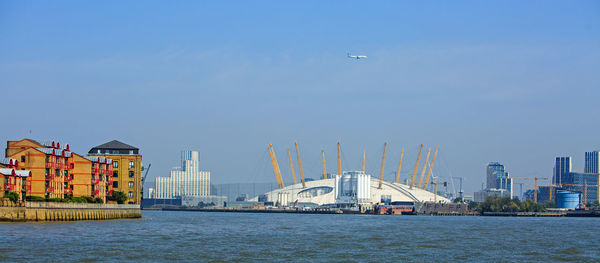 Scenic view of river by buildings against sky