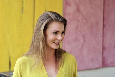 Portrait of a smiling young woman against yellow wall