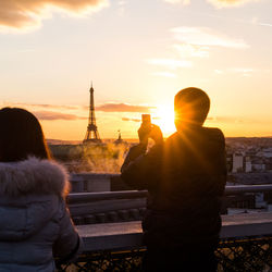 Rear view of silhouette man and woman taking photo of eiffel tower