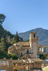 Buildings in city against clear blue sky