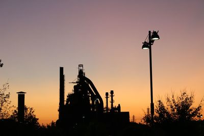 Low angle view of silhouette cranes against clear sky